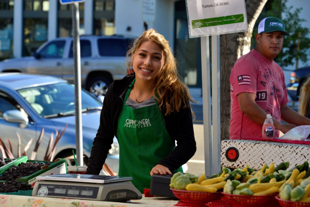 Active adults browsing fresh produce at the Danville farmers market, a community perk for those downsizing to The Nova