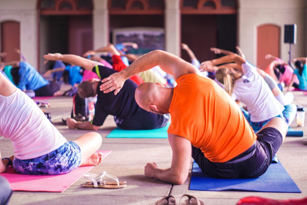 Group of active adults doing yoga on a sunny rooftop terrace, the social side of wellness after downsizing to The Nova