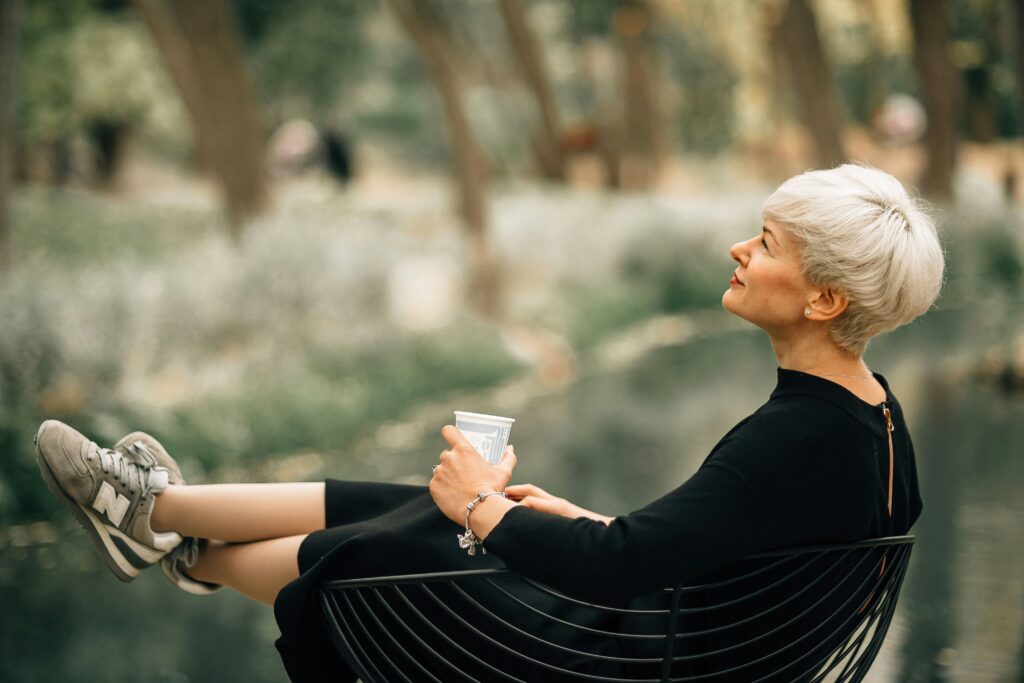 Relaxed active adult enjoying coffee on a terrace, free of chores after downsizing to a lock-and-leave home at The Nova